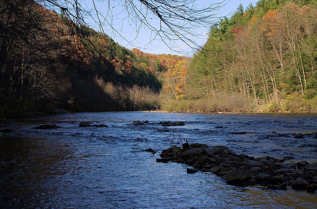 The Lehigh River running through the gorge between hillsides turning gold and rust in autumn.