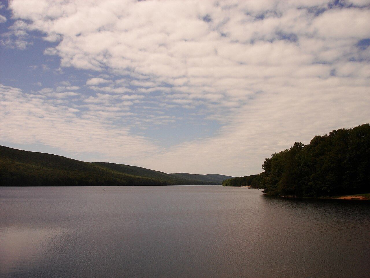 Mauch Chunk Lake at dusk, forested ridges either side under a broken sky.