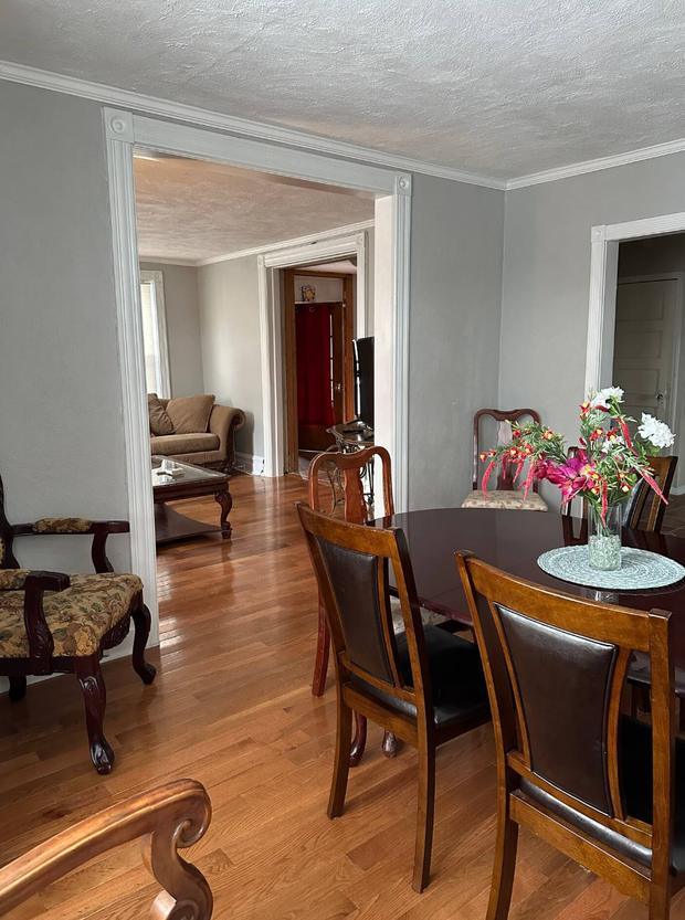 Dining room with a polished wood table, upholstered chairs and hardwood floors opening to the sitting room.