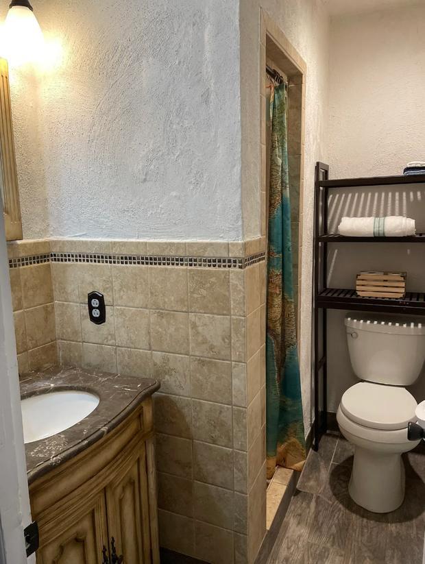 Tiled bathroom with a stone vanity, mirror and shelved towels.