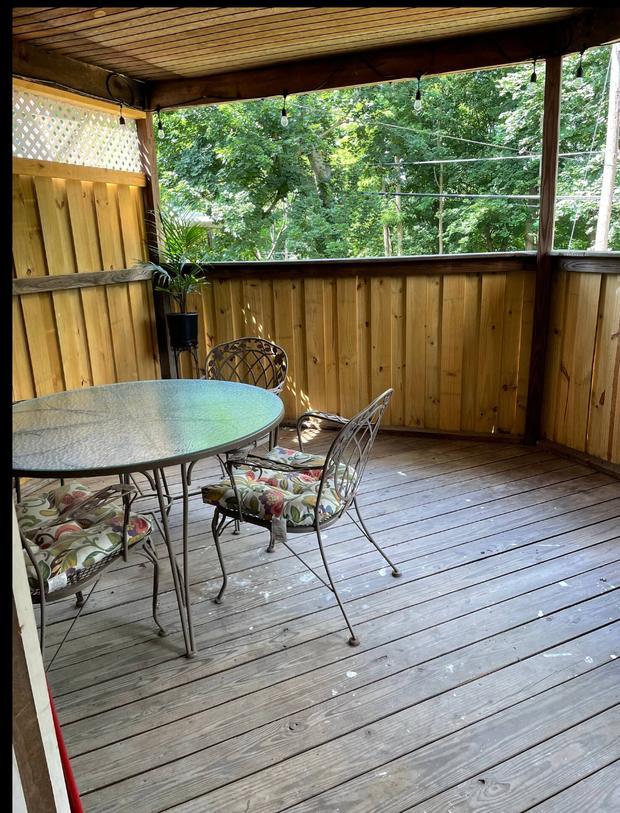 Screened back porch with a bistro table and chairs and a wood plank floor.