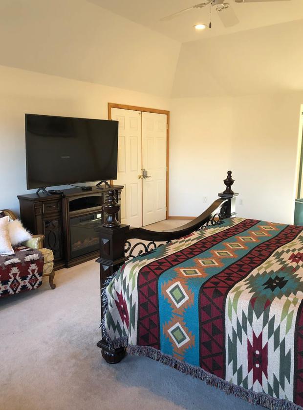 Bedroom with a patterned southwestern bedspread, dresser and television.