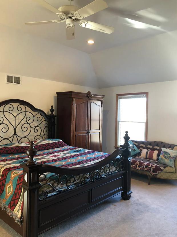 Bedroom with a dark carved four-poster bed, wardrobe and a bright window.