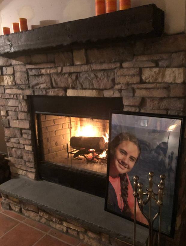 Wood burning fireplace set in stone with a framed photograph on the mantel.