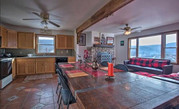 Open-plan kitchen and living area with an exposed beam, tiled floor and a view to the mountains.