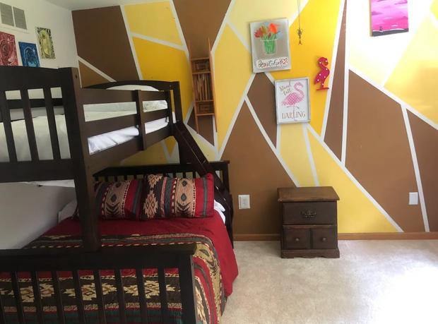 Children's bedroom with bunk beds and a bold yellow and white geometric wall.